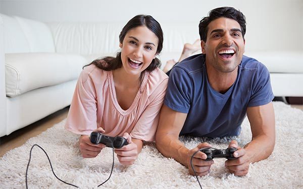 Zwei Personen liegen auf Teppich und spielen
