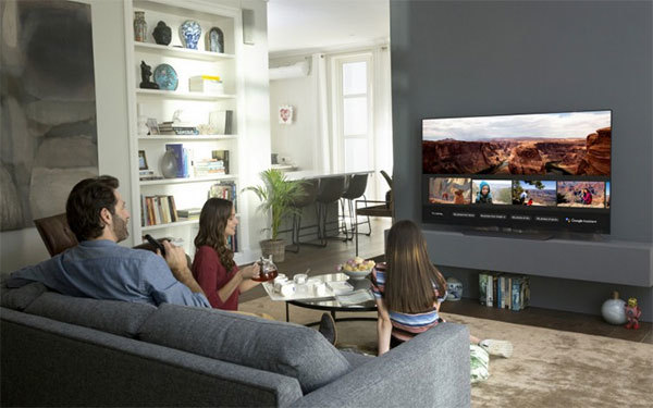 Familie sitzt im Wohnzimmer vor dem Fernseher