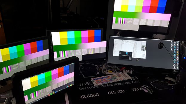 LG 27UK850-W (Mitte) neben Broadcast-Referenzbildschirmen am Testbildgenerator