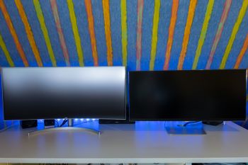 38WK95C-W und 34UM95 im Vergleich. Die Krümmung des 38WK95C-W fängt mehr Lichtquellen ein und verteilt diese flächiger auf dem Panel. Ein klarer (unvermeidbarer) Nachteil der Krümmung