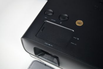 Klappe, hinter der sich die Regler für Zoom, Fokus, Lens-Shift h/v befinden